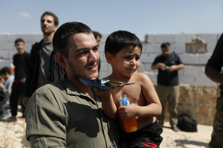 Một tay súng phiến quân vừa được phóng thích khỏi nhà tù Syria bế con trai của mình sau khi tới El Eis, phía nam Aleppo.