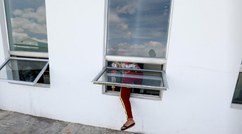 Nữ công nhân trèo qua cửa sổ trở về nơi làm việc sau giờ ăn trưa.