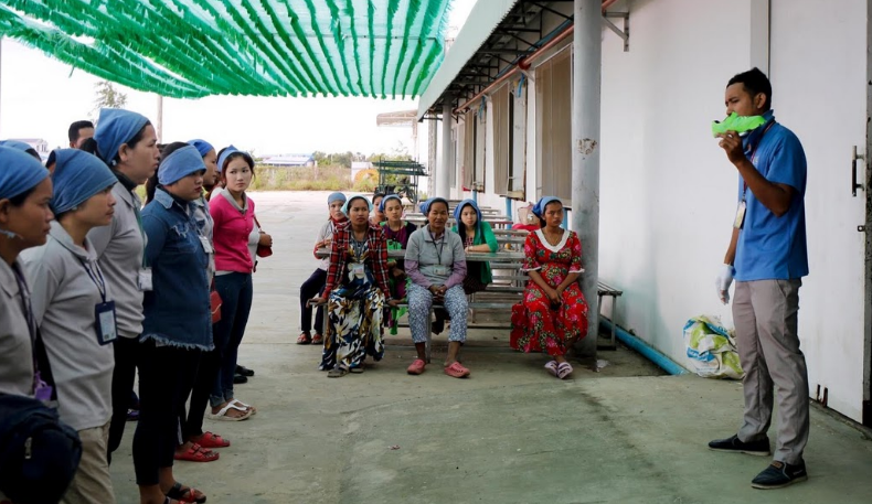 Một người giám sát của đội may hướng dẫn các công nhân trước khi họ bắt đầu vào ca làm việc.