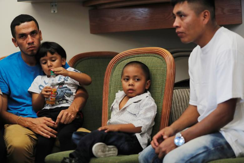  Javier (trái), 30 tuổi đến từ Honduras, bế con trai William 4 tuổi trong khi Adan, 26 tuổi đến từ Guatemala, ngồi cạnh cậu con trai 4 tuổi Juan sau khi được đoàn tụ hôm 11/7. Ảnh: Reuters.