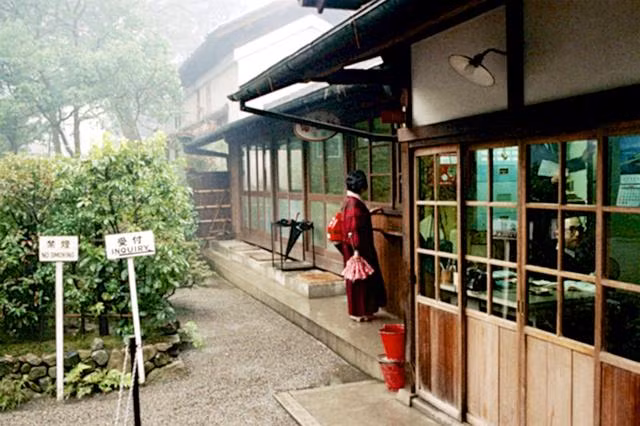 Một người phụ nữ vận trang phục kimono truyền thống của Nhật Bản đứng trước cửa một nhà hàng vào một ngày mưa. Ảnh Sina