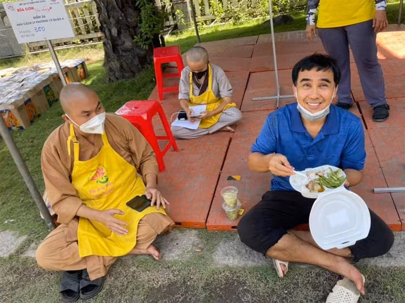 Quyền Linh tham gia các bếp ăn thiện nguyện, đi phát quà từ thiện cho người dân trong từng con hẻm. Có lần đi thiện nguyện, anh ngồi bệt ăn vội bữa cơm. Ảnh: FBNV