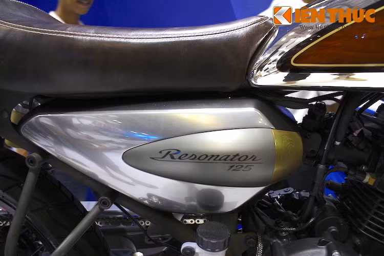 Dòng chữ Resonator sơn trên các tấm che hai bên thân xe sử dụng font chữ đầy tính cổ điển, nằm bên lại là một tấm ốp đồng chạm khắc hoa văn khác.