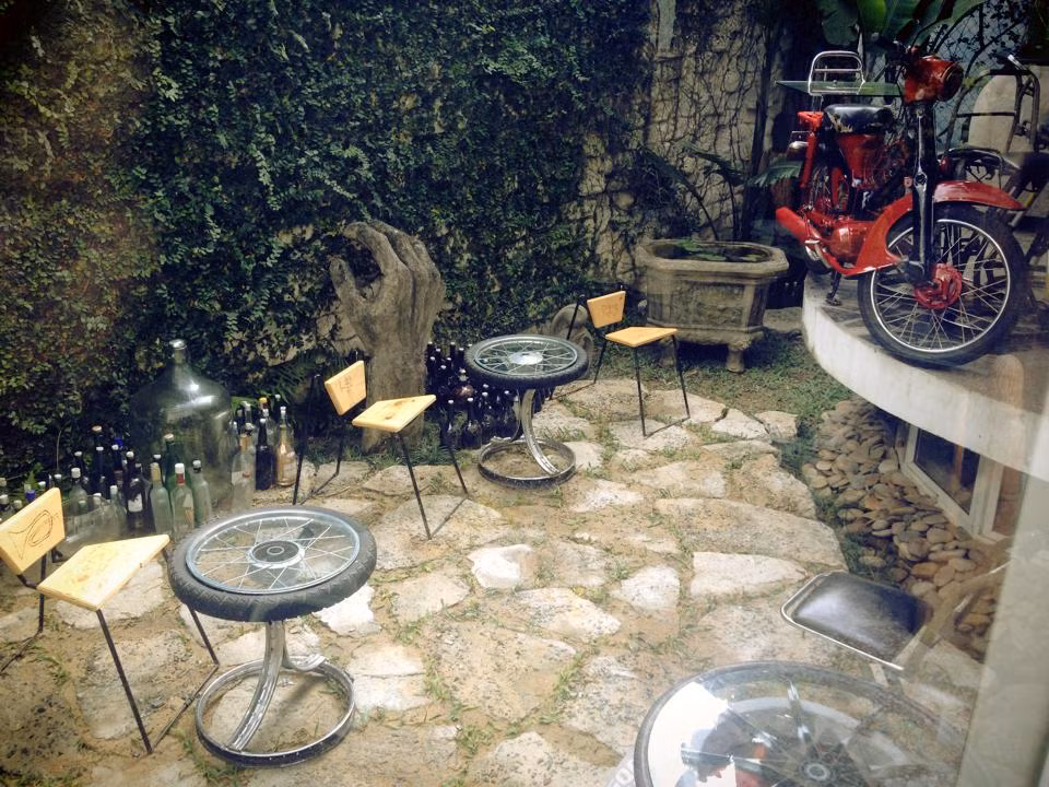 Những chiếc bàn đơn làm từ lốp và vành xe gắn máy đã qua sử dụng. Gần đó là hình ảnh chiếc xe cup 50 những năm 60-70 thế kỷ trước.