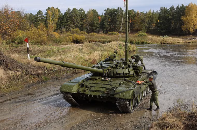 Các binh sĩ hỗ trợ diễn tập đang kiểm tra bên ngoài xe tăng.