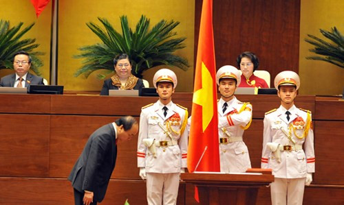 Thủ tướng Nguyễn Xuân Phúc cúi chào trước cờ Tổ quốc và bước lên bục tuyên thệ, đặt tay trên Hiến pháp