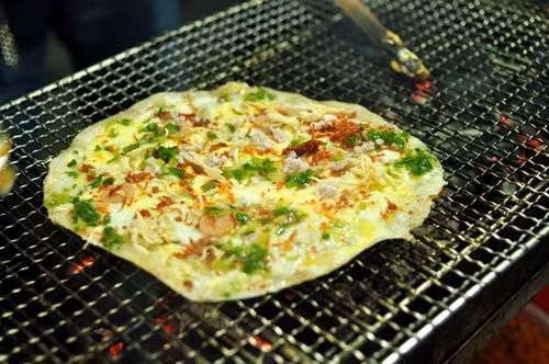 Bánh tráng nướng – Bánh tráng nướng là món ăn du nhập từ miền lạnh Đà Lạt nên không quá khó hiểu khi đây cũng là món ăn vặt cực thích hợp trong tiết trời Hà Nội tháng Ba. “Pizza Việt Nam” thường được bán gần các trường học, hoặc bạn có thể thưởng thức ở Hàng Tre, nơi bán bánh tráng nướng gần như đầu tiên tại Hà thành.