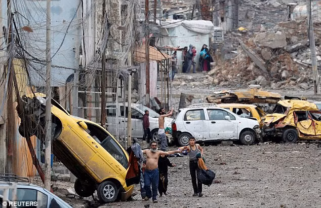 Người đàn ông cởi áo để cho các binh sỹ Iraq biết ông không đeo đai bom tự sát đang ra dấu trong lúc chạy khỏi vùng IS kiểm soát. Ảnh Daily Mail