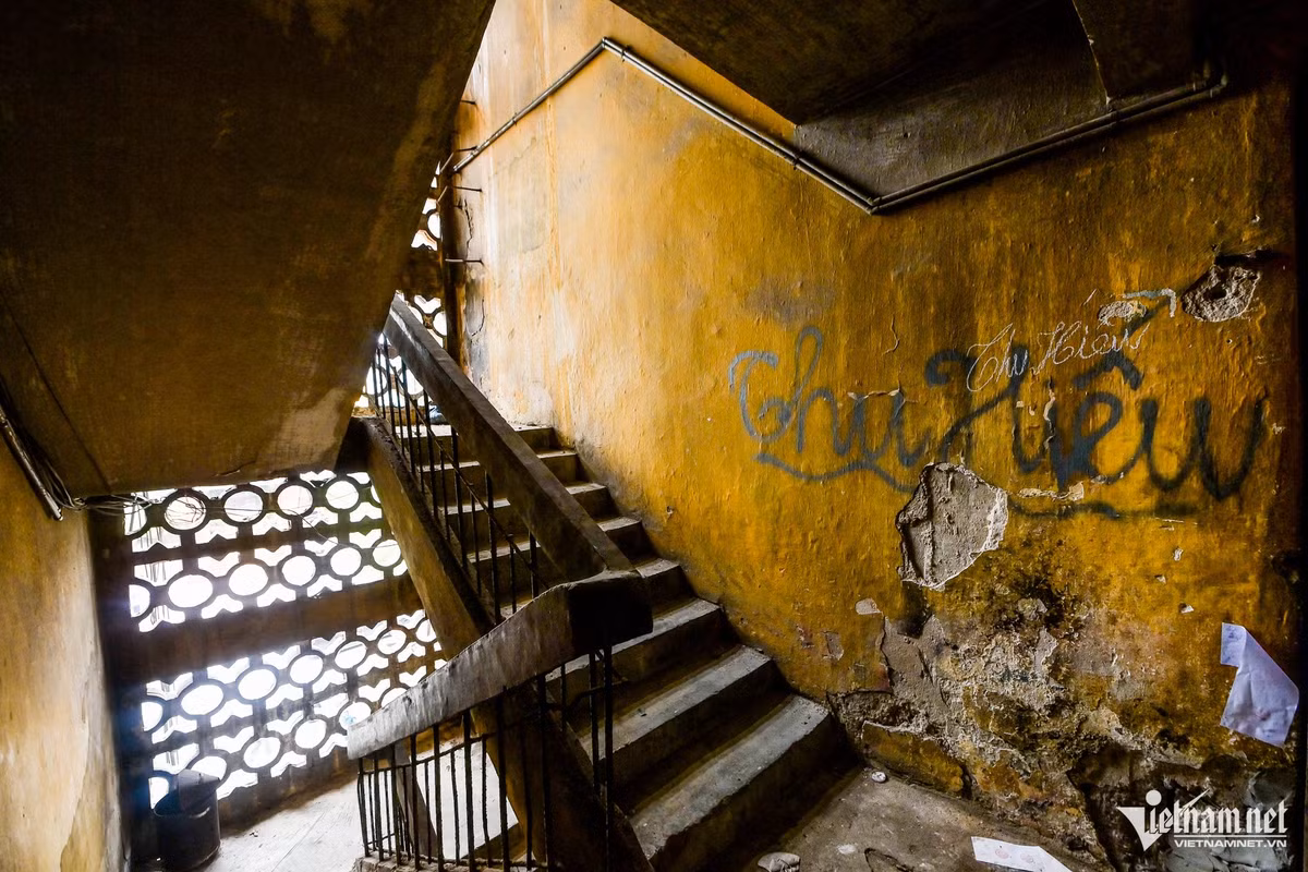 Cầu thang lên các tầng tối tăm, ẩm thấp, tường lở loét từng mảng lớn.