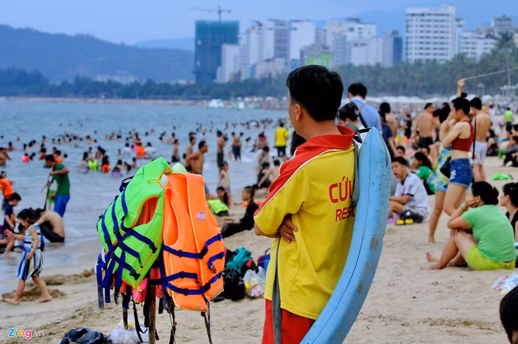 Nhân viên cứu hộ bãi biển chăm chú theo dõi du khách đề phòng bất trắc xảy ra. Anh còn tranh thủ kiếm thêm bằng công việc cho thuê áo phao, giá 20.000 đồng/chiếc.