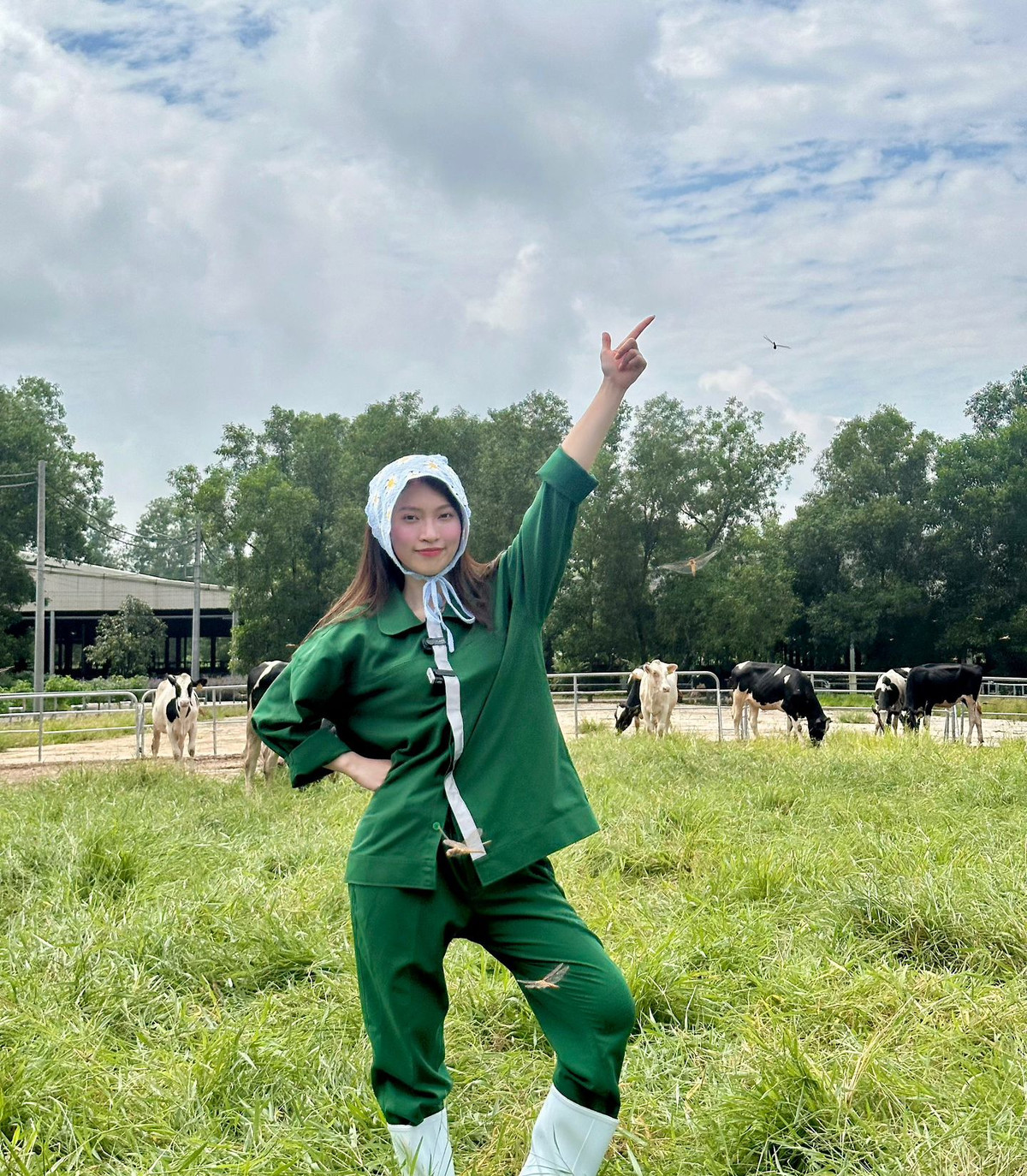 Cô nàng diện bộ đồ màu xanh đặc trưng của những công nhân làm trong trang trại, tạo dáng nhí nhảnh giữa đồng cỏ cùng đàn bò sữa.