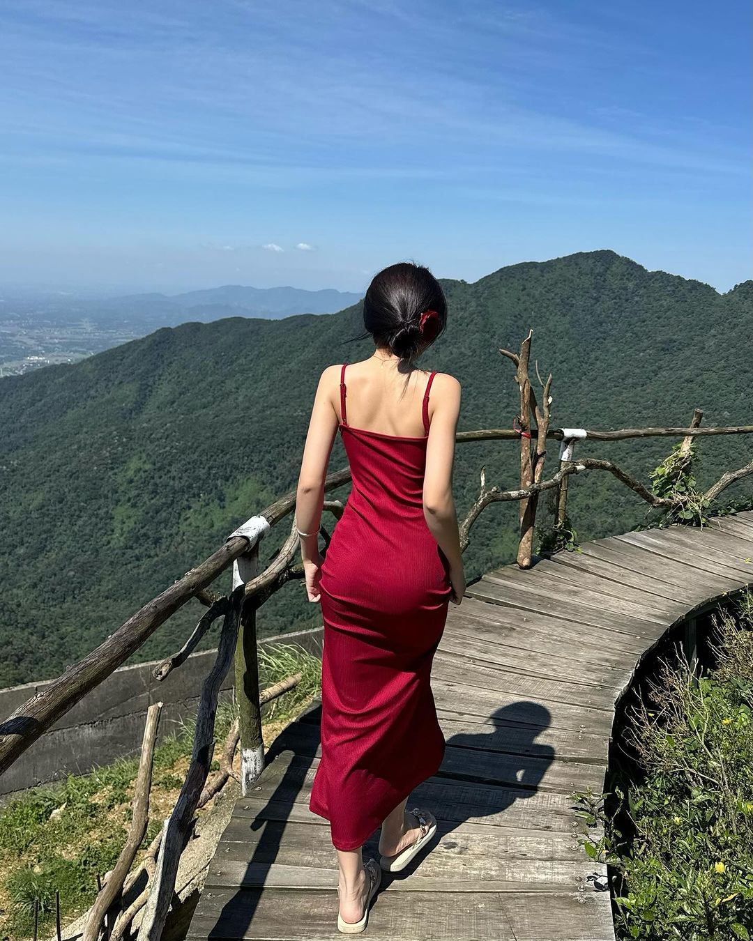 Diện chiếc váy hai dây màu đỏ nổi bật, nữ Tiktoker khoe dáng giữa khung cảnh mộng mơ, phía sau là rừng núi.
