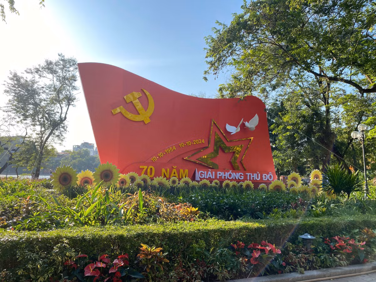 Tấm áp phích lớn được trang trí, thiết kế tỉ mỉ với hình ảnh lá cờ Đảng cùng ngôi sao vàng, cánh chim câu đại diện cho hòa bình, xung quanh là hoa hướng dương tượng trưng cho sức sống, cho sự tích cực hướng đến tương lai tươi đẹp.