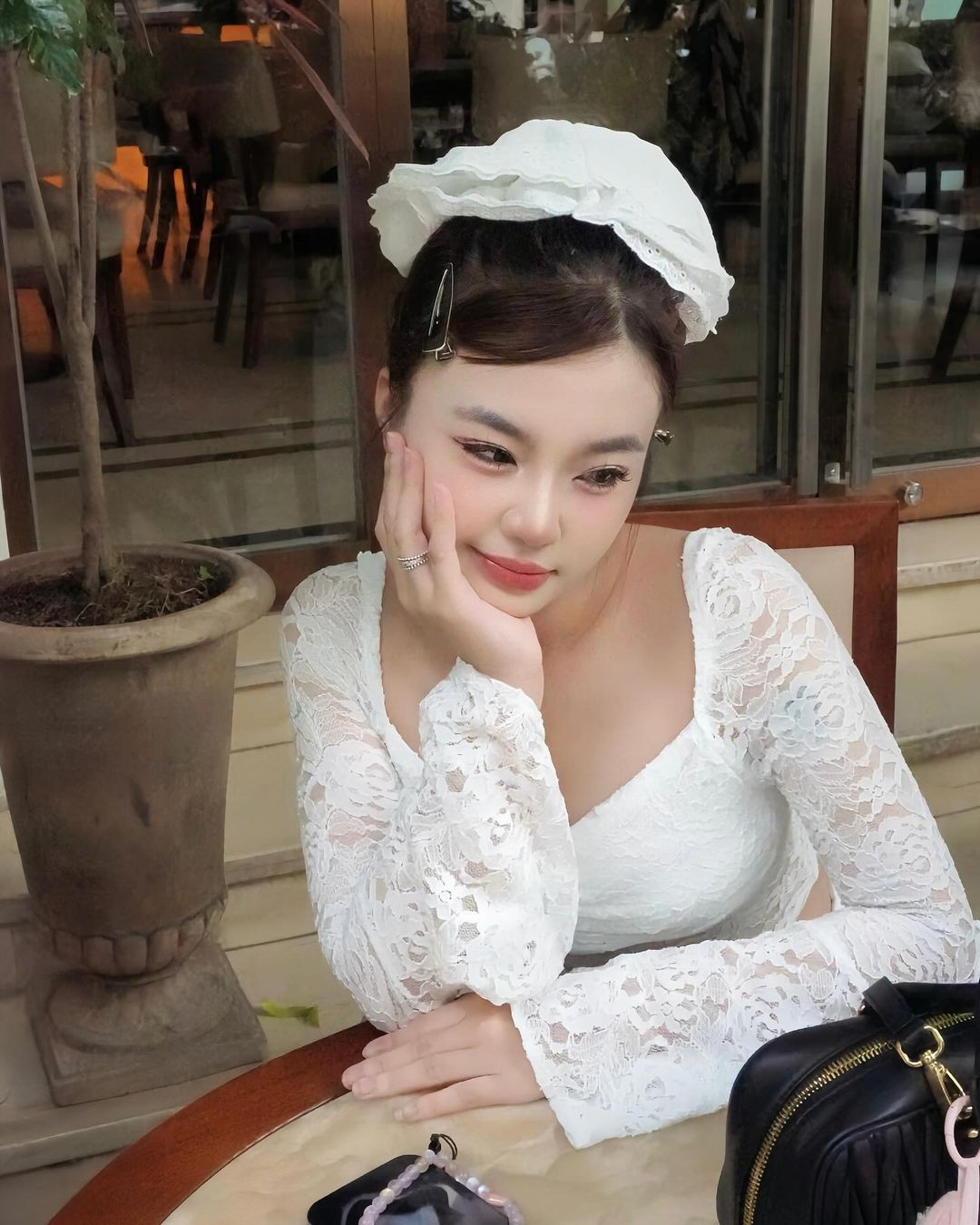 Pô lựa chọn set váy với chất liệu ren trắng tiểu thư, phần ống tay áo xòe bánh bèo, chân váy được thiết kế nhiều tầng xinh xắn.