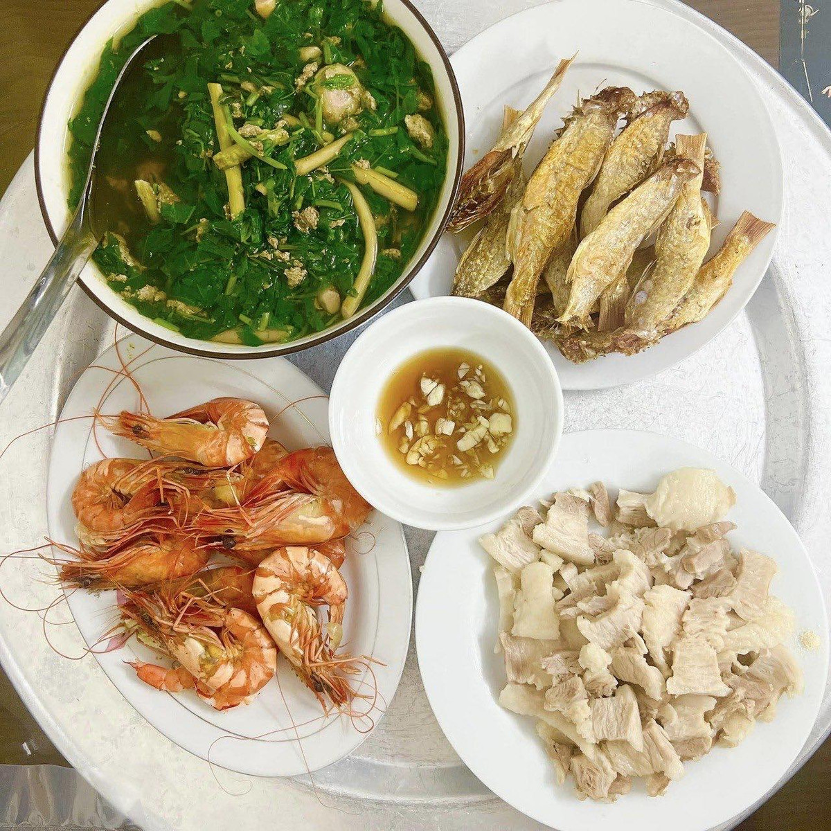 Mâm cơm đầy đủ thịt, hải sản được bày biện khéo léo.