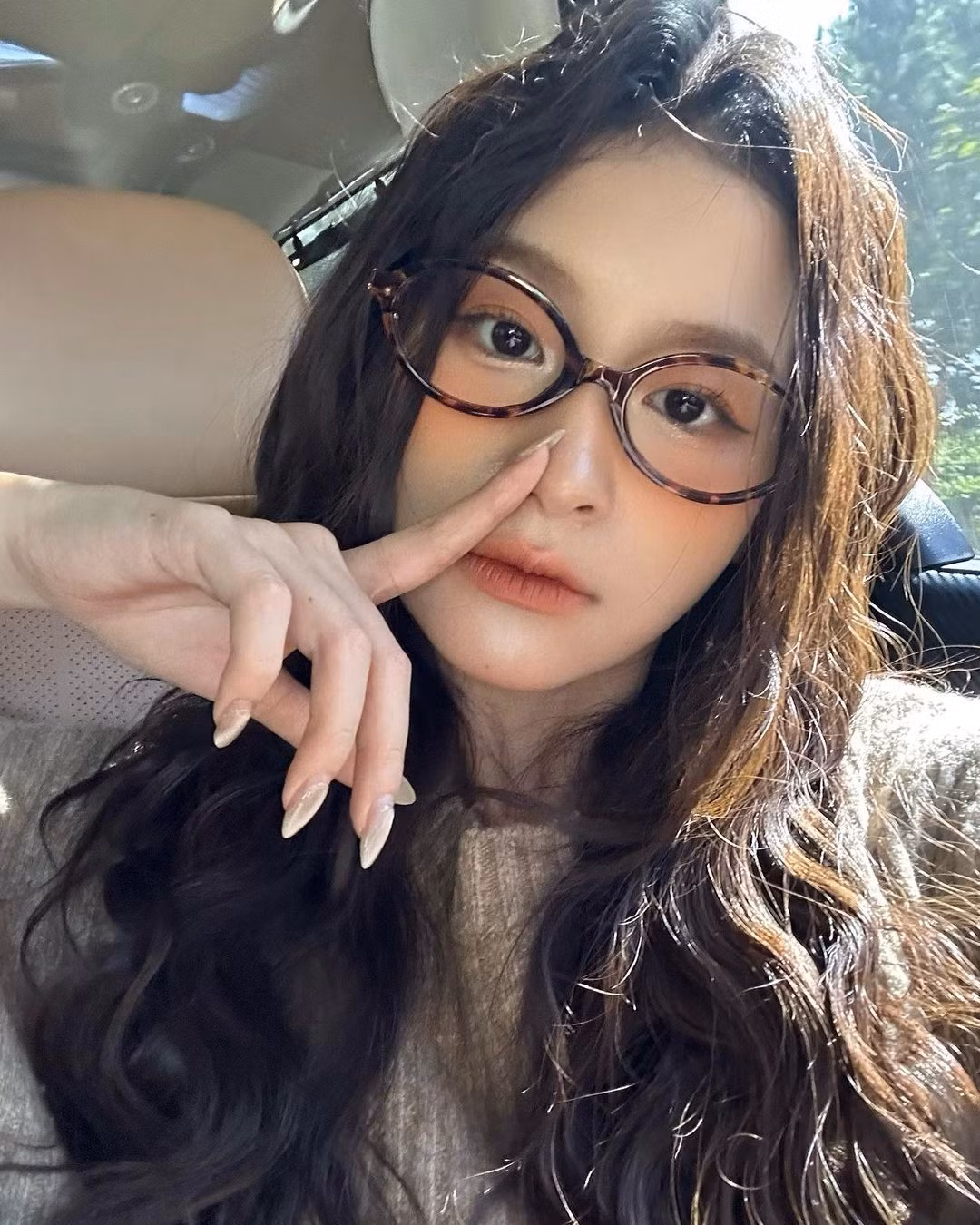 Cùng với lớp make-up tone cam, mái tóc được làm xoăn sóng, gọng kính như điểm nhấn cho phong cách của cô nàng.