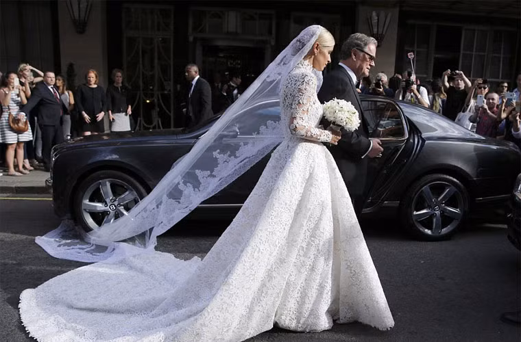 Chưa kể, chiếc voan cài đầu cô dâu dài quết đất, khiến nó bị vướng cả vào bánh chiếc xe Bentley khi cha cô dẫn cô ra xe tới nơi cử hành hôn lễ.