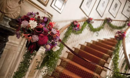 Những bó hoa sắc màu buộc cố định vào cầu thang tạo hình vòng cung đẹp mắt.