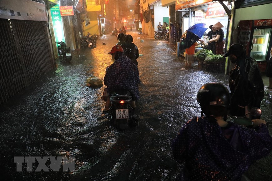 Phố Bùi Xương Trạch ngập nặng ngập khiến nhiều người không đi qua được. (Ảnh: Tuấn Anh/TTXVN)