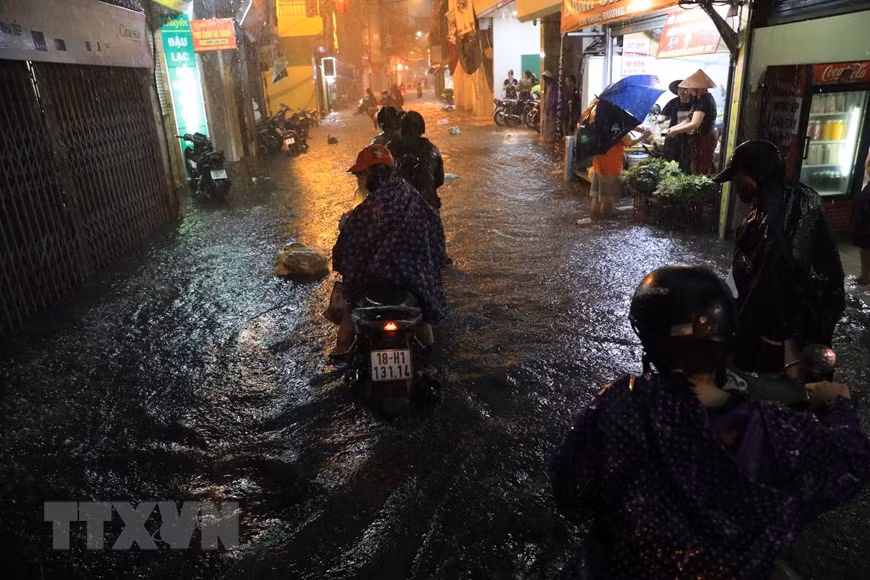 Phố Bùi Xương Trạch ngập nặng ngập khiến nhiều người không đi qua được. (Ảnh: Tuấn Anh/TTXVN)