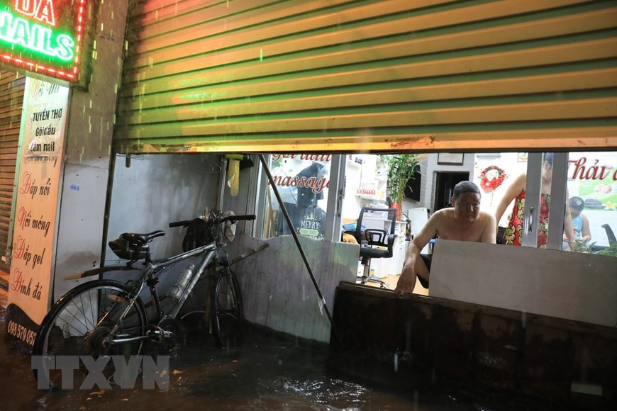 Phố Bùi Xương Trạch ngập nặng khiến người dân phải tìm cách ngăn không cho nước tràn vào nhà. (Ảnh: Tuấn Anh/TTXVN)