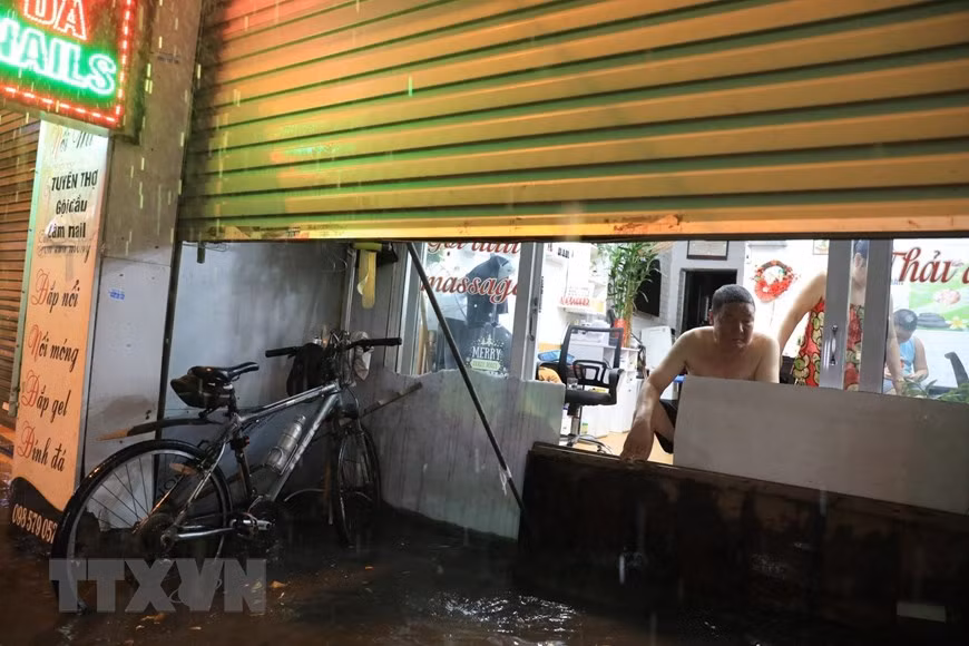 Phố Bùi Xương Trạch ngập nặng khiến người dân phải tìm cách ngăn không cho nước tràn vào nhà. (Ảnh: Tuấn Anh/TTXVN)