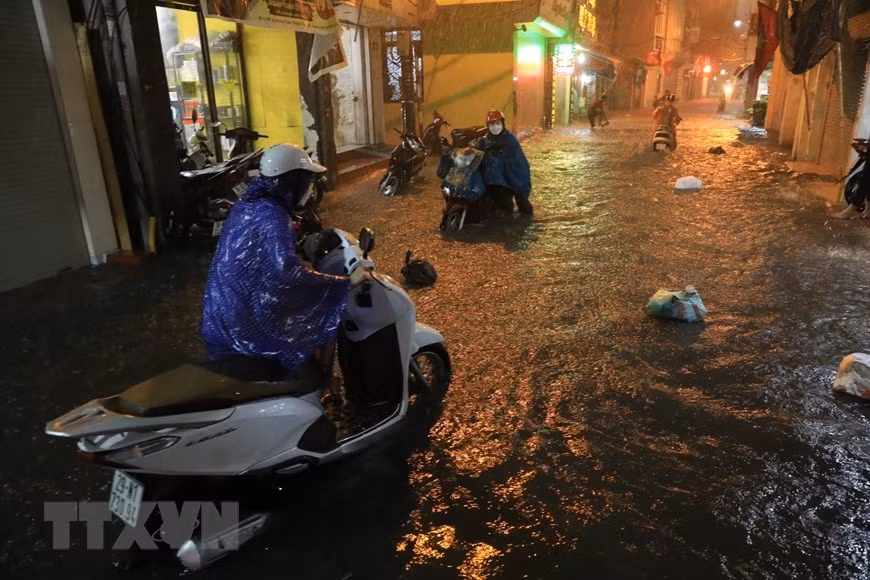 Phố Bùi Xương Trạch ngập nặng khiến nhiều người đi lại khó khăn. (Ảnh: Tuấn Anh/TTXVN)