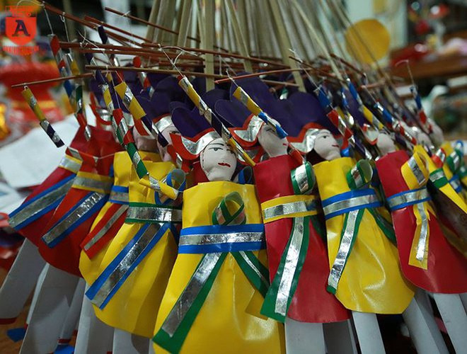 Theo truyện xưa để lại, tháng 8 là mùa nông nhàn, dịp Trung Thu cũng là lúc học sinh bắt đầu tựu trường. Với mong muốn cho con cháu thành đạt, người dân hay mua ông tiến sĩ giấy về bày cùng mâm ngũ quả trong đêm trăng rằm. Về khuya, trẻ nhỏ phá cỗ, còn tiến sĩ giấy được để trên bàn học. Ảnh: Tintucvietnam.