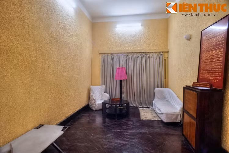 Căn phòng có diện tích khoảng 15 mét vuông, có ghế bành, bàn gỗ, tủ đựng tài liệu, giường vải cùng một số vật dụng khác.