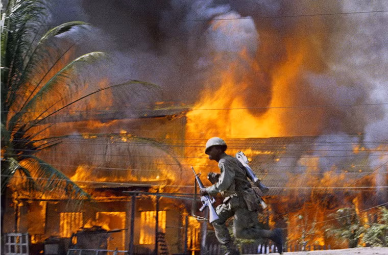 Lính Mỹ vội vã chạy ngang qua một ngôi nhà bốc cháy ngùn ngụt ở Sài Gòn tháng 6/1968.