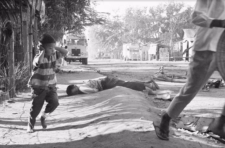 Một em bé sợ hãi chạy tránh đạn,, ảnh chụp ngày 31/1/1968. Phía sau là thi thể một dân thường thiệt mạng vì trúng đạn.