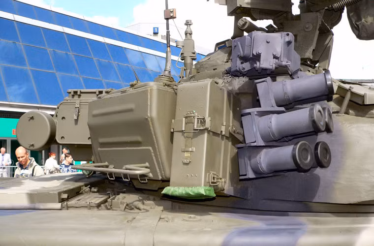 Còn đây là 6/12 ống phóng màn sương – nó được phun ra khi Shtora phát hiện ra rằng xe tăng đã bị "điểm mặt" bởi các thiết bị ngắm laser. Màn sương chỉ chưa cần tới 3 giây đã có thể hình thành và kéo dài khoảng 20 giây. Phạm vi triển khai của màn sương từ 50-70 mét. Màn sương này sẽ gây nhiễu các thiết bị chỉ định bằng laser cũng như ngụy trang cho xe tăng trước các thiết bị ngắm bắn quang học.