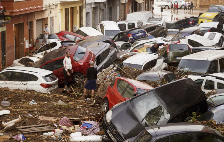 Người dân nhìn những chiếc ô tô chất đống sau khi bị lũ cuốn trôi ở Valencia ngày 30/10.