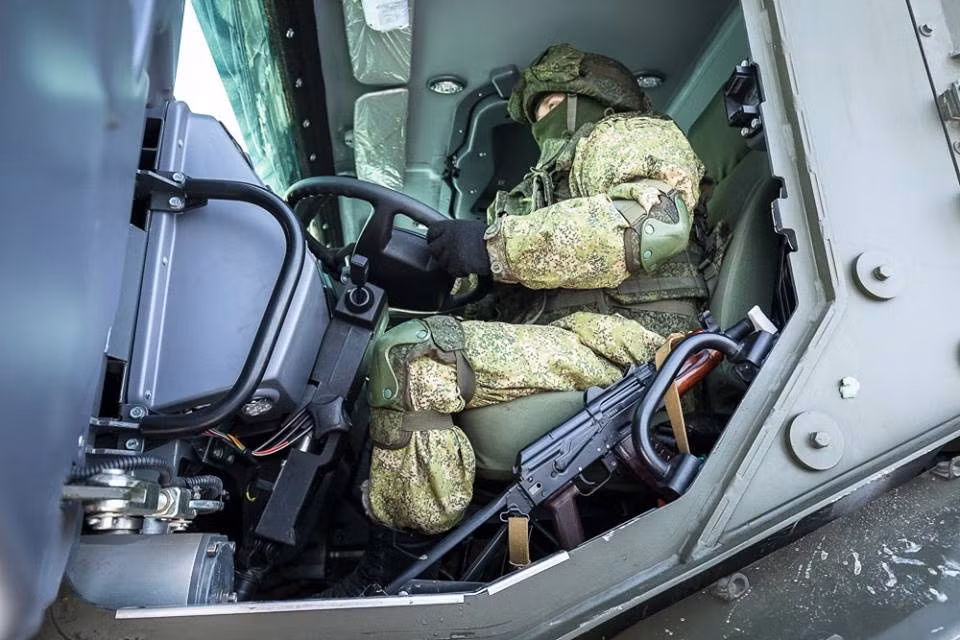 Mặc dù mặc bộ quân phục rộng thùng thình cùng giáp bảo vệ nhưng lái xe trông ngồi khá thoải mái, bên cạnh anh ta là khẩu tiểu liên AKS-74U. Nguồn ảnh: Sputnik