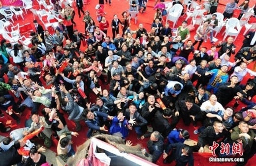 Bất chấp giá lạnh, vị đại gia vẫn hào hứng cởi trần, đứng trên giàn giá cao hơn 100m mà rải bao lì xì xuống. Ảnh: Chinanews