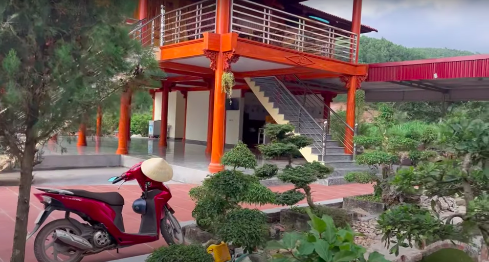 Phần sân của ngôi nhà có tổng diện tích 310m2, được lát gạch đỏ, trang trí nhiều bonsai và nhiều loại cây trồng lâu năm.