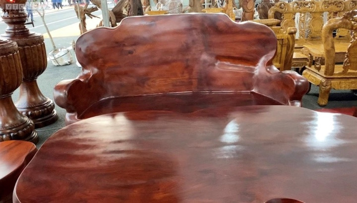 Nét độc đáo của bộ bàn ghế gỗ hương này là những đường cong uốn lượn, nương theo thân dáng tự nhiên của cây gỗ nguyên khối. Ảnh: VTCNews