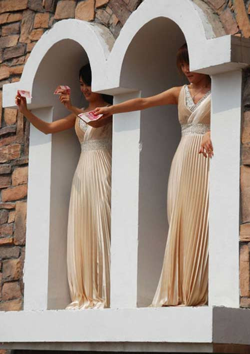 Trước đó, một đại gia nhà đất ở Giang Tô (Trung Quốc) nghĩ ra chiêu thuê 3 mỹ nhân đứng trên cao rải tiền để thu hút khách tham quan. Ảnh: Qianzhan