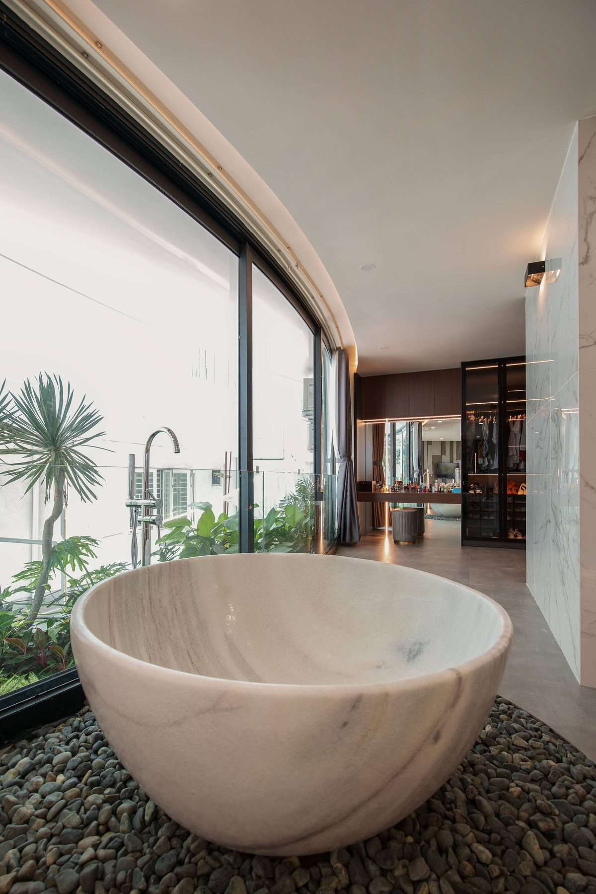 Bồn tắm tròn bằng đá cẩm thạch, có tầm nhìn hướng ra khu vườn nhỏ phía trước.