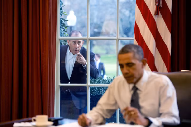 Ngày 7/12/2015: Diễn viên hài Jerry Seinfeld gõ cửa sổ của phòng Bầu dục nơi Tổng thống Obama đang ngồi để bắt đầu một cảnh quay trong loạt phim của anh.