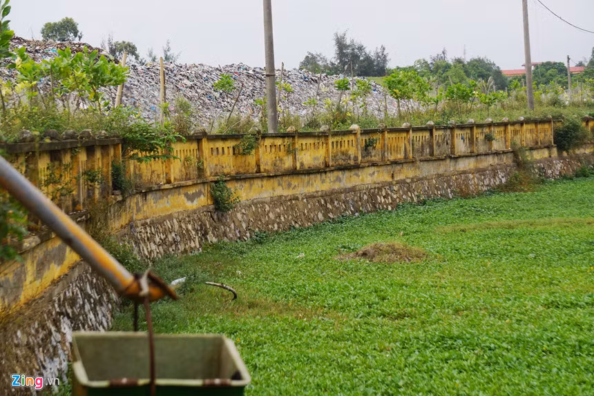 Hàng rào cao khoảng 2 m không che chắn nổi bãi rác với khu vực ruộng của người dân. Theo phản ánh, nhiều hộ đã phải bỏ hoang ruộng lúa quanh đây vì nước thải gây ô nhiễm, chết lúa.