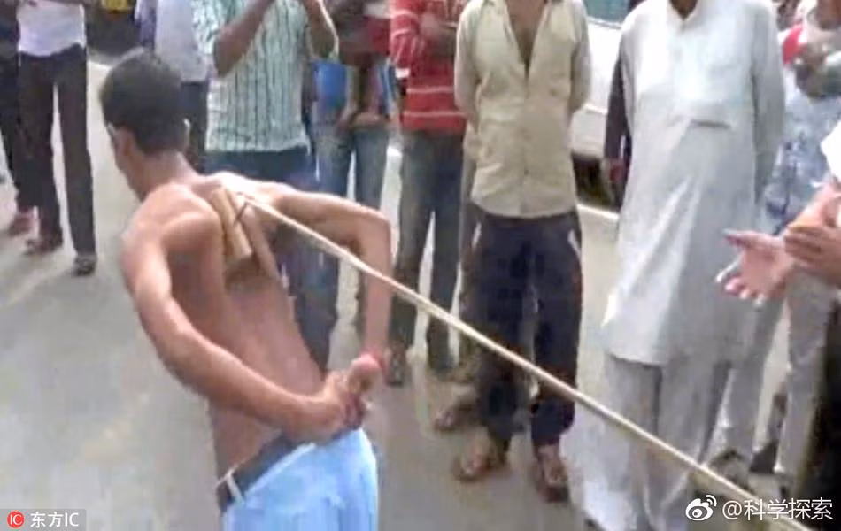 Người đàn ông Ấn Độ này đang dùng xương bả vai của mình để kéo vật nặng trước sự cổ vũ của những người đứng xem. (Nguồn Sina)