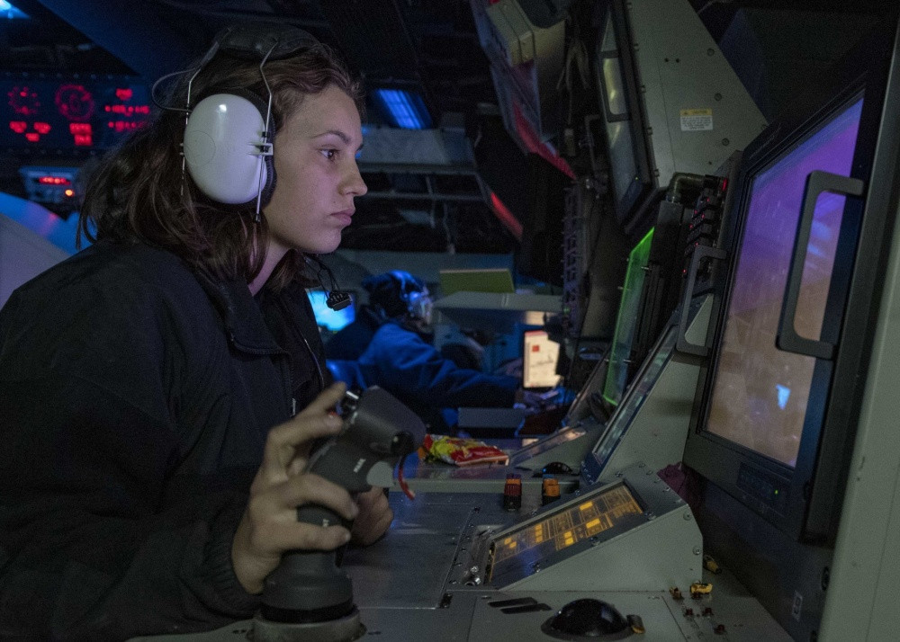 Một thủy thủ đang chăm chú theo dõi màn hình điều khiển pháo 127 mm trên tàu. Chiến hạm USS Mustin sử dụng pháo 127 mm nâng cấp với tháp pháo cải tiến để tăng khả năng tàng hình, mở rộng tầm bắn lên 34 km so với 27 km của phiên bản cũ.