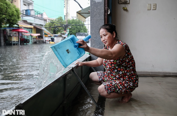 Bà Lê Thị Bé Mười (54 tuổi) phải dùng đồ hốt rác để tát nước ra khỏi nhà. "Tôi làm giúp việc ở đây mấy năm rồi, cũng khá quen thuộc với việc tát nước này mỗi lúc mưa lớn", bà Mười chia sẻ.