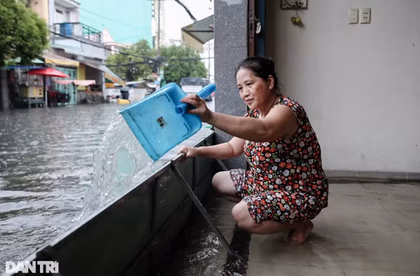 Bà Lê Thị Bé Mười (54 tuổi) phải dùng đồ hốt rác để tát nước ra khỏi nhà. "Tôi làm giúp việc ở đây mấy năm rồi, cũng khá quen thuộc với việc tát nước này mỗi lúc mưa lớn", bà Mười chia sẻ.