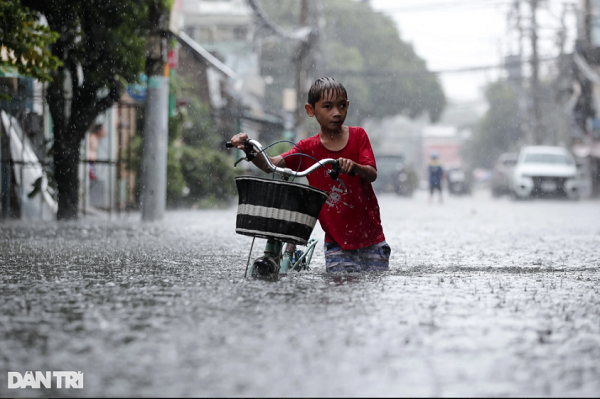 Một em bé bì bõm dắt bộ qua đoạn ngập trên đường Dương Văn Cam.