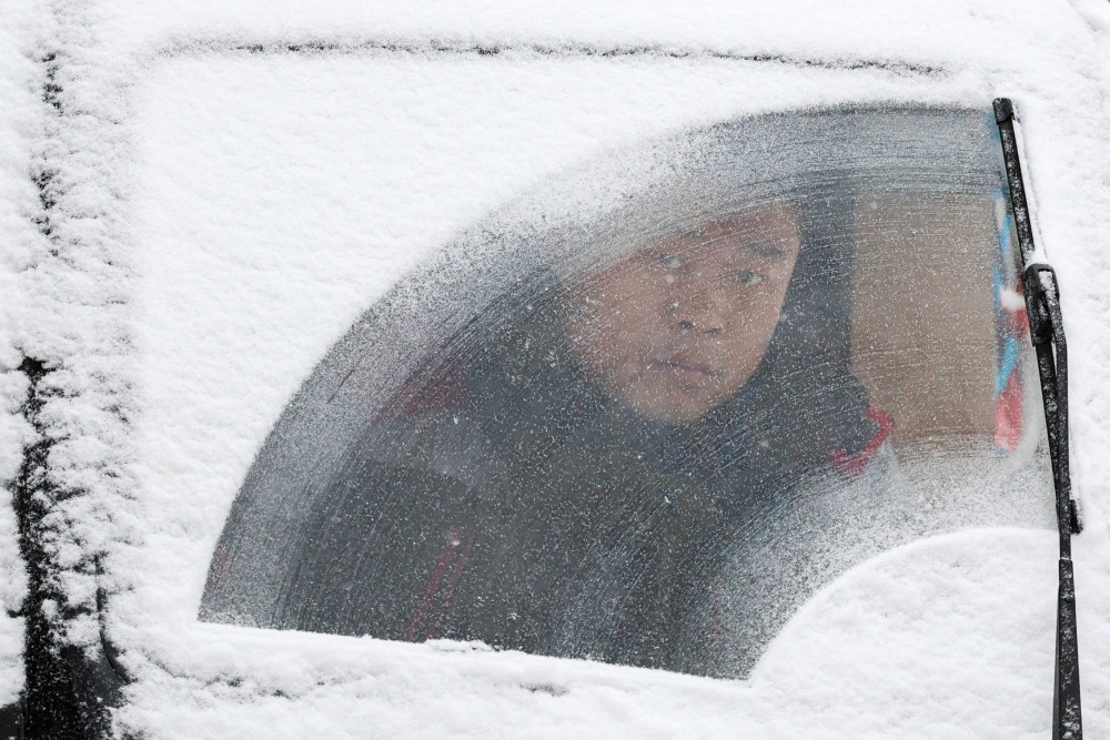 Một người dân Bắc Kinh trong chiếc xe phủ đầy tuyết. Ảnh: Reuters.