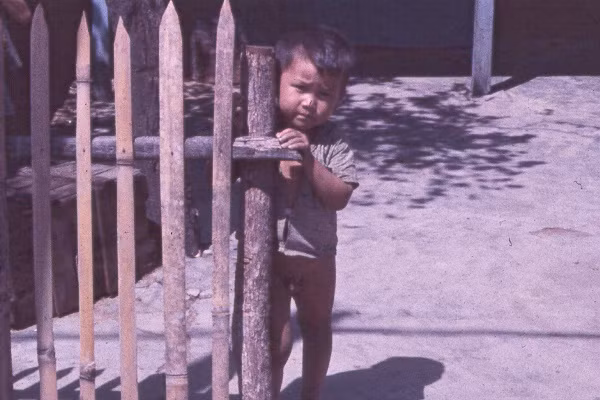 Em bé bên cổng một ngôi nhà vùng nông thôn ngoại ô Sài Gòn. Ảnh: Oldspooksandspies.org