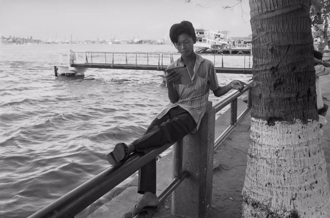 Cậu bé đọc sách trên bến Bạch Đằng, 27/3/1990. Ảnh: Magnumphotos.com