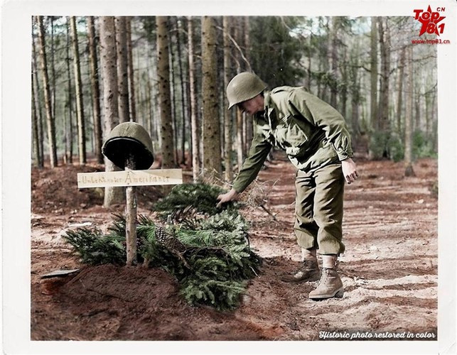 Một người lính đang phủ lá cây lên ngôi mộ người đồng đội vừa hi sinh.